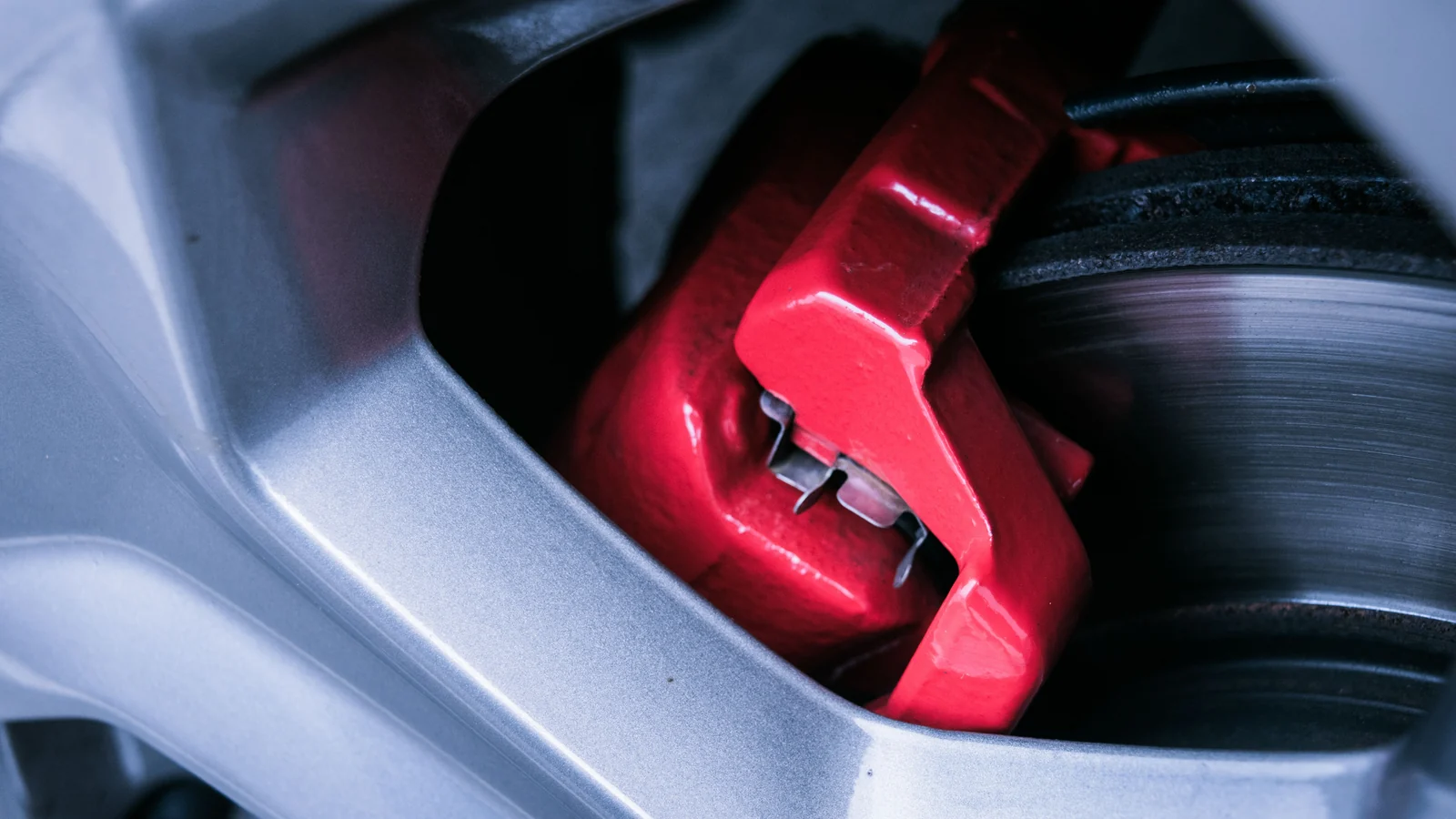 Illustrative stock image of a red brake caliper beside a brake disc.