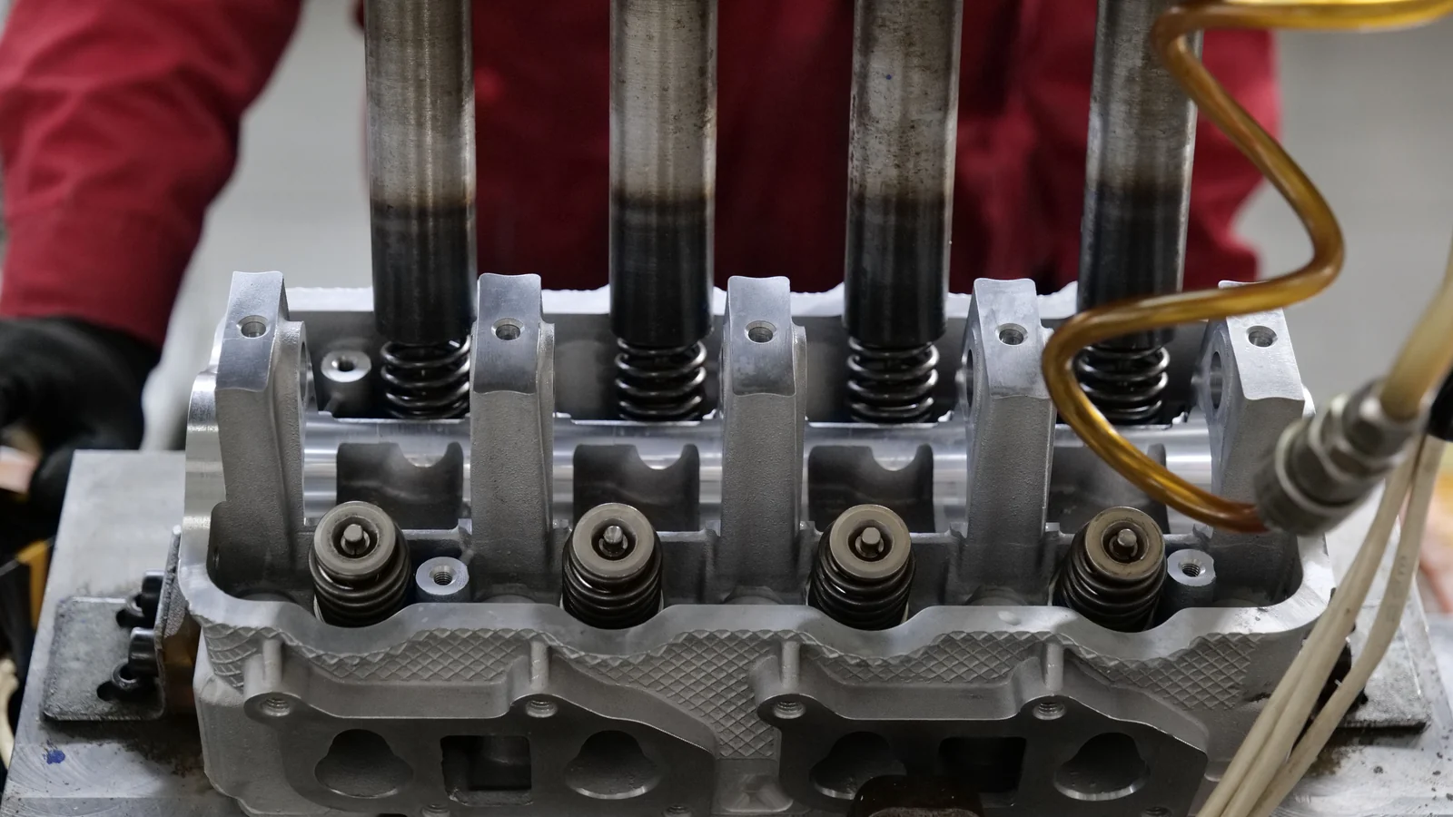 Illustrative stock image of an engine cylinder head with exposed valve springs on a workbench.