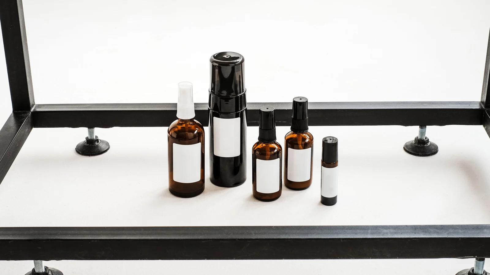 Assorted amber and dark bottles on a white table beside a window.