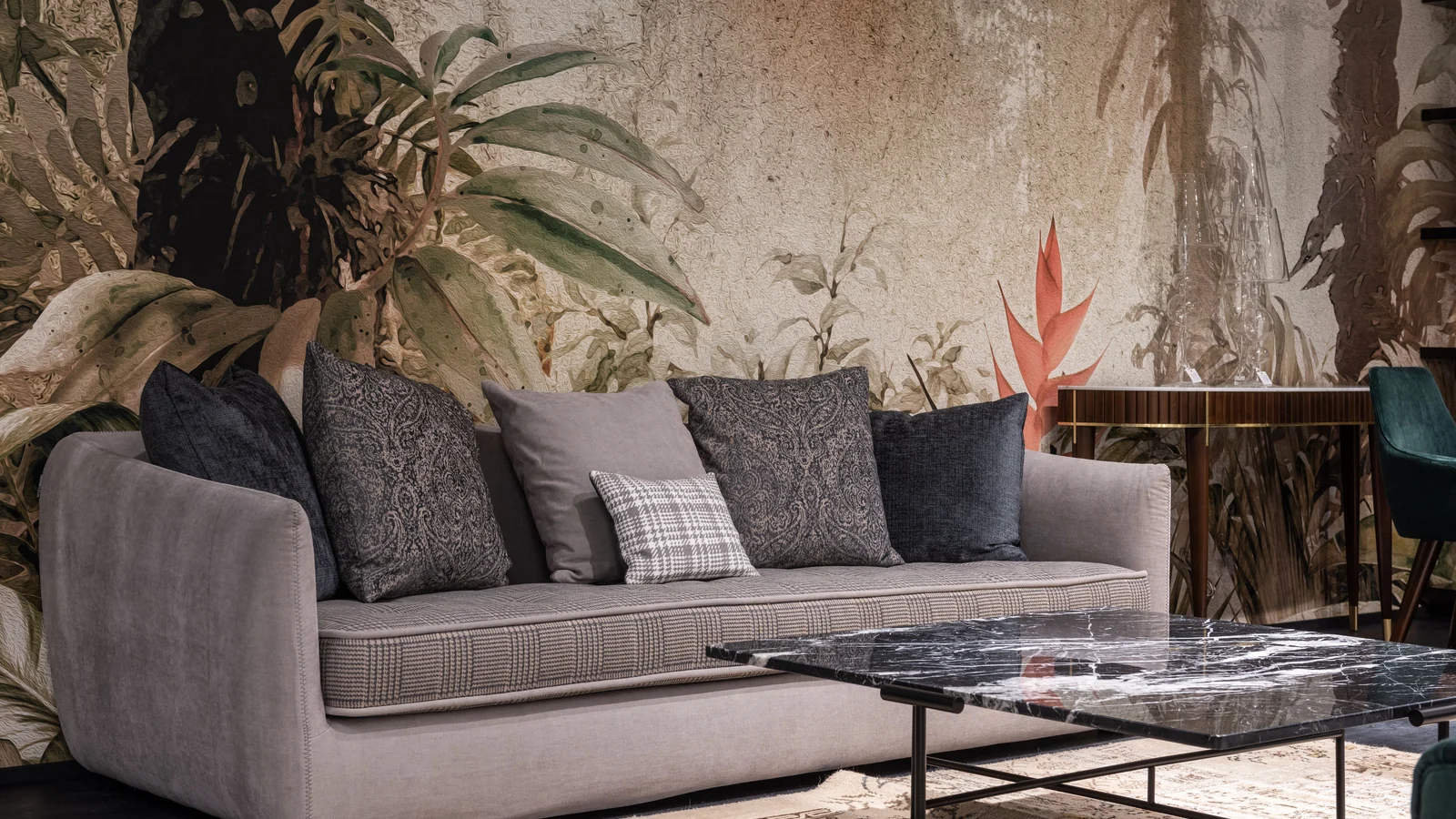 A grey sofa with cushions beside dark coffee tables and botanical wall decoration.