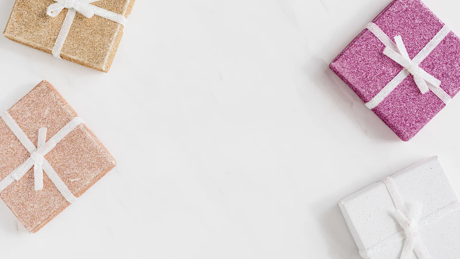 Glittery gift boxes tied with white ribbons on a white background.